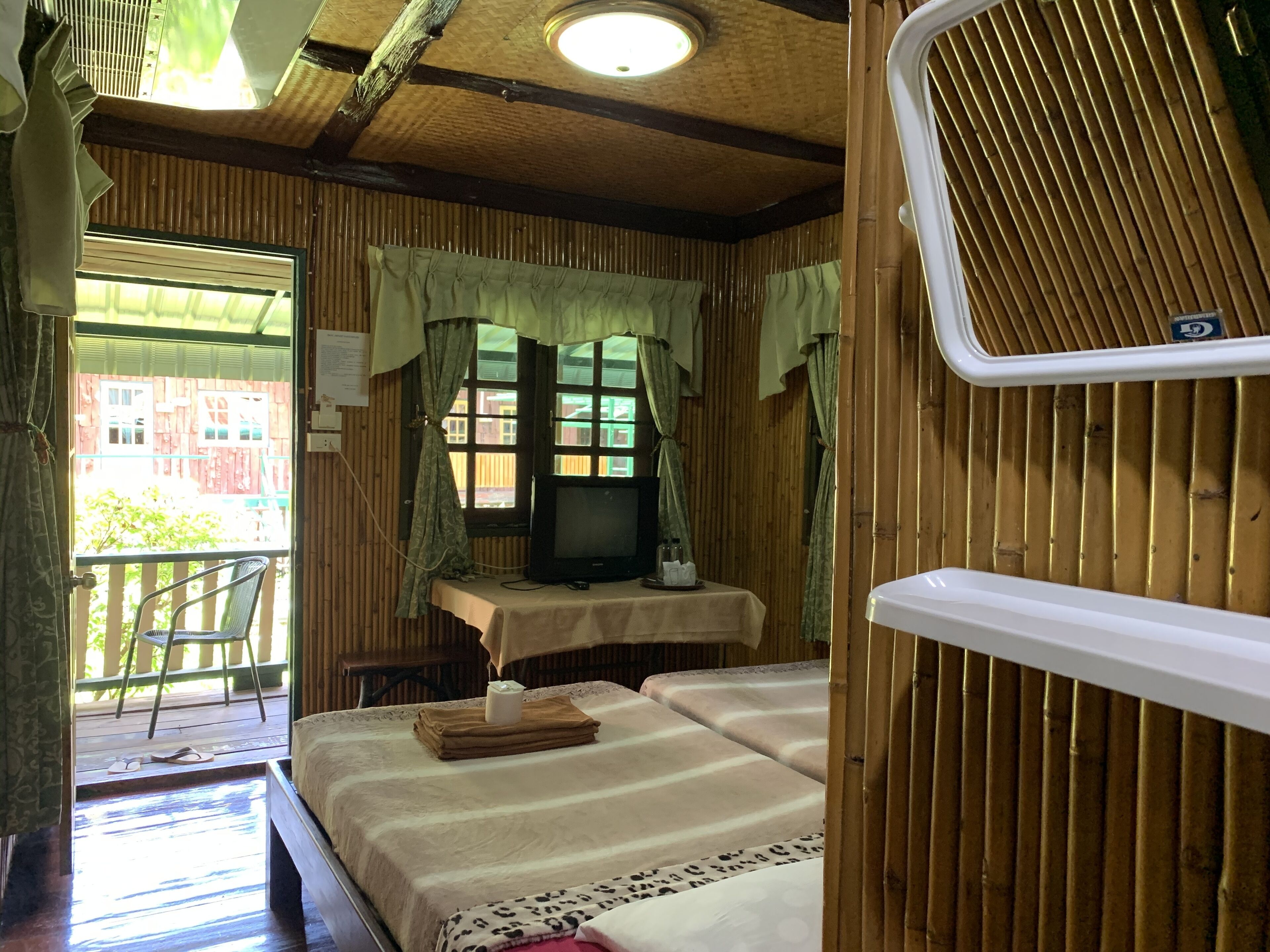 A cozy room with a bed, a small table with a TV, and a window with curtains.