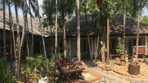 A courtyard with a tiled floor, palm trees, and various statues. - Sam's House Guesthouse (Kanchanaburi)