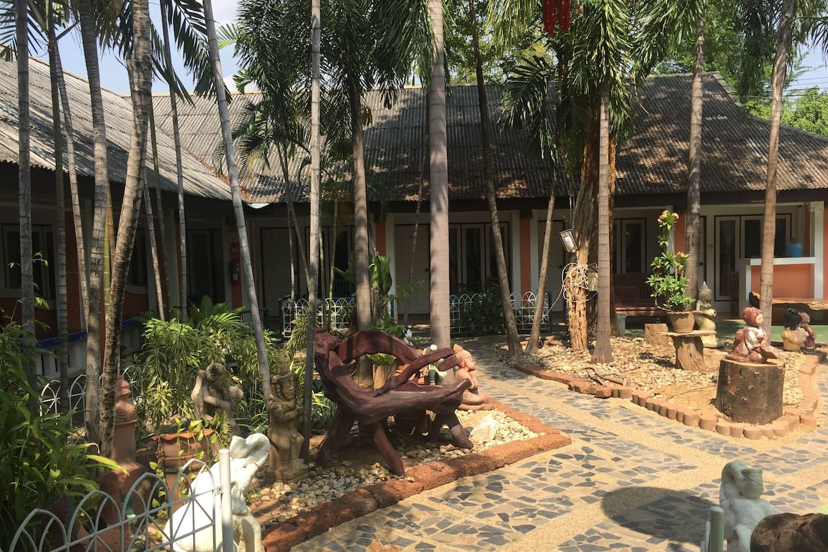 Un patio con suelo de baldosas, palmeras y varias estatuas.
