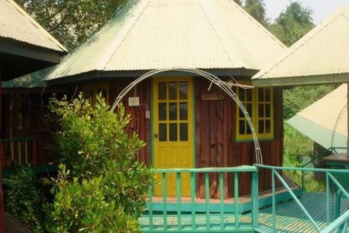 Una pequeña estructura de madera con una puerta amarilla y una barandilla verde.