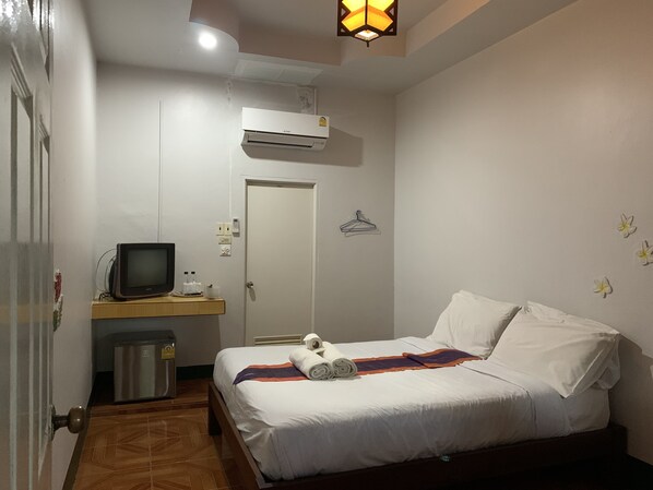 A bedroom with a bed, a TV, a heater, and a wall-mounted air conditioner.