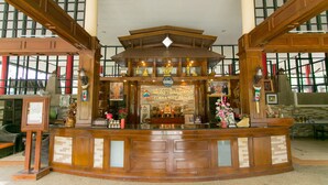 A reception area with a wooden counter, framed artwork, and a sign for Woss Talat Seoti Forra Hill Resort. - Forra Hill Resort (Mueang Loei)