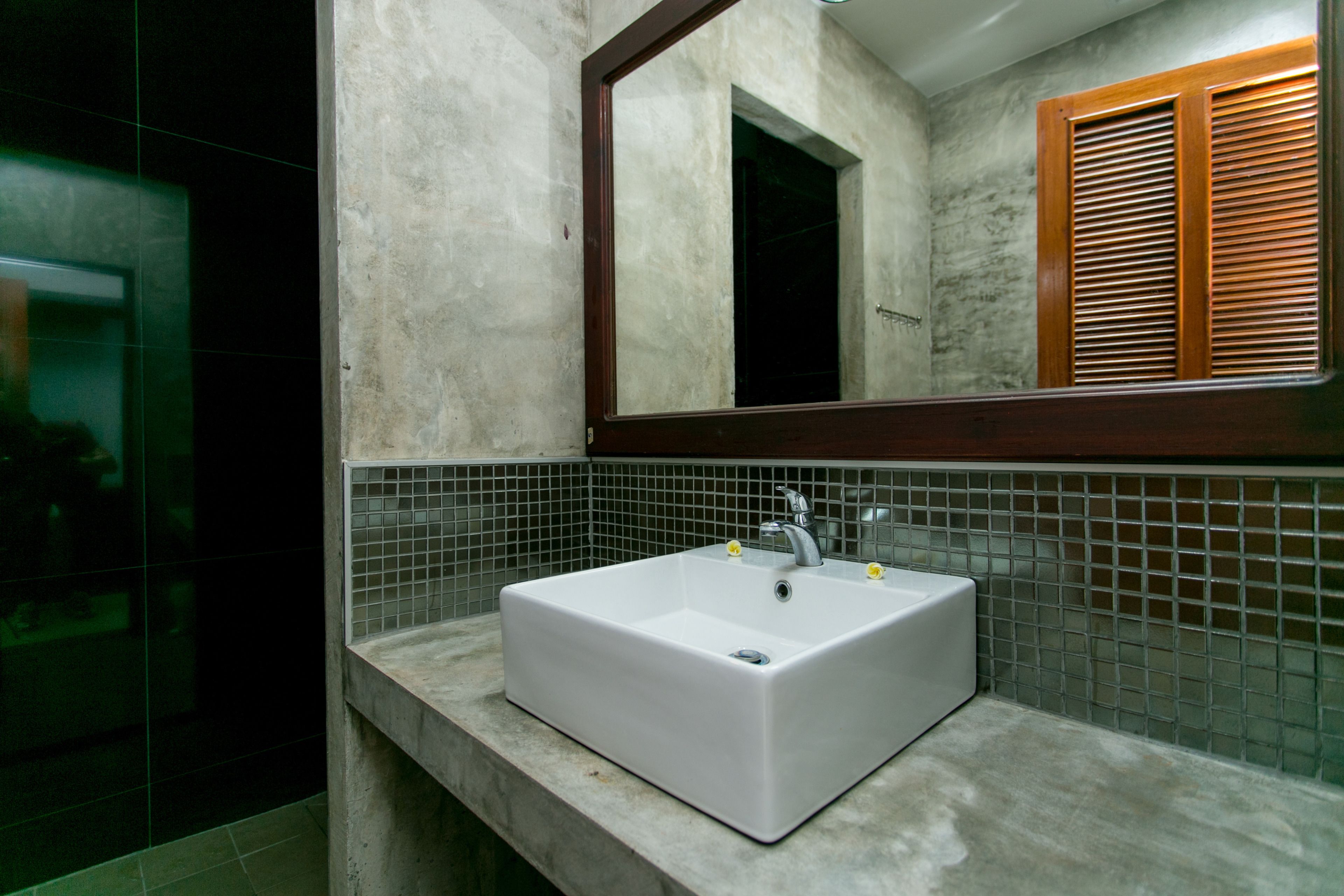 A bathroom with a white sink, a mirror, and a tiled backsplash.