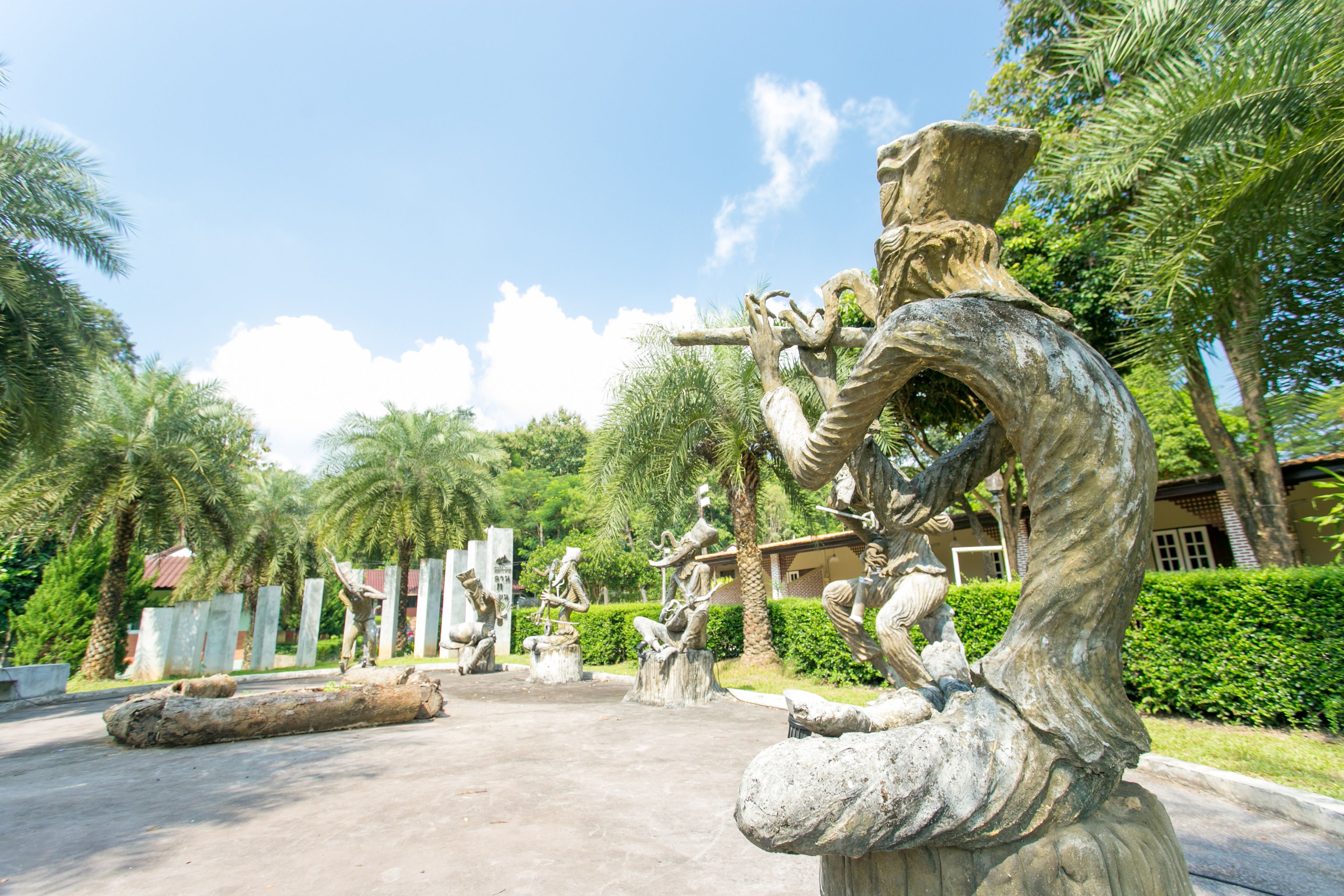 Un jardín de esculturas con varias figuras de piedra y un tronco grande.