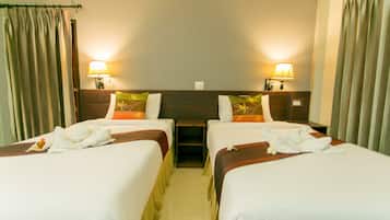 Habitación de hotel con dos camas, cada una con una almohada y una toalla. Hay dos lámparas de noche y una mesita entre las camas.