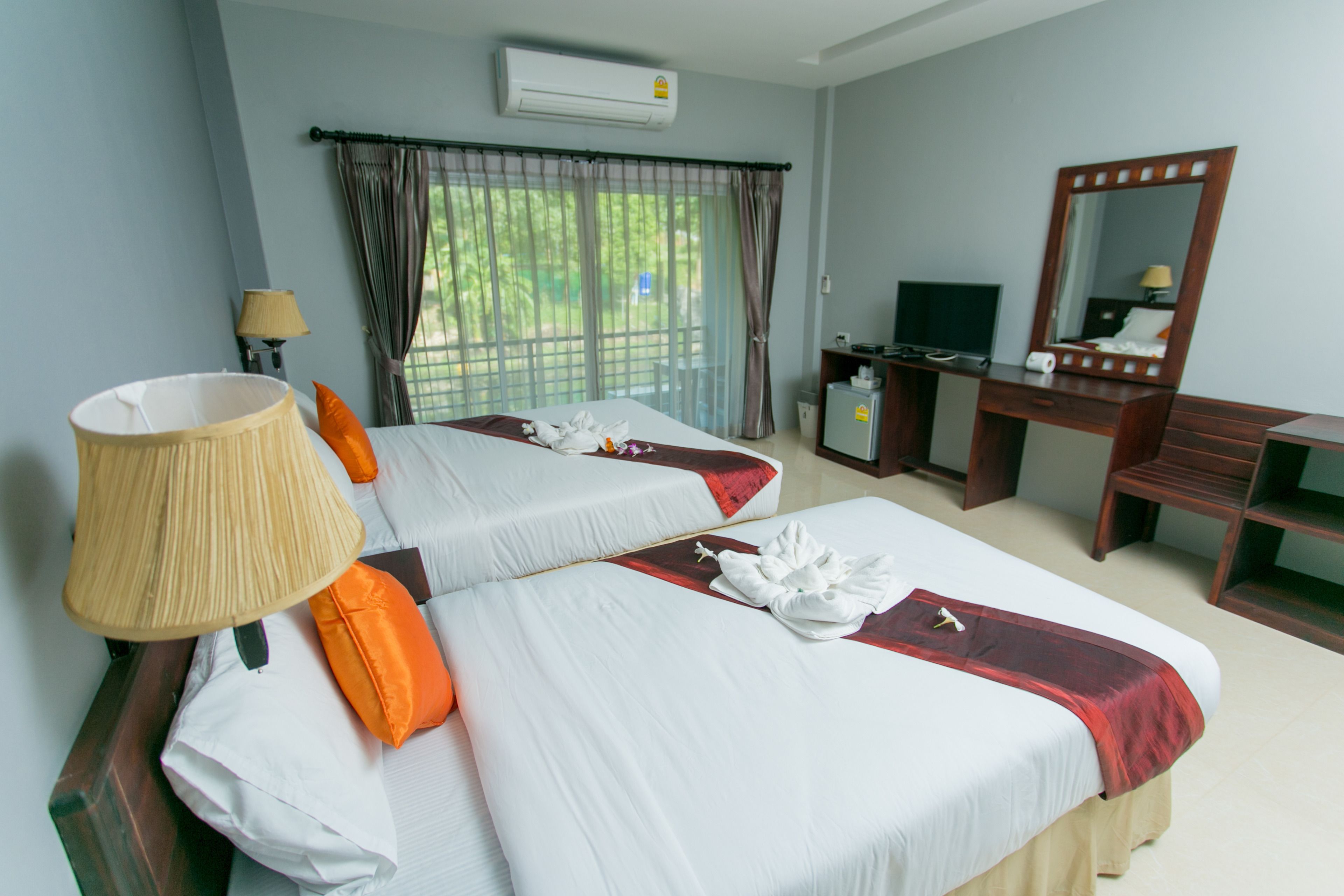 Quarto de hotel com duas camas, uma escrivaninha, uma cadeira, uma televisão e um aparelho de ar condicionado.