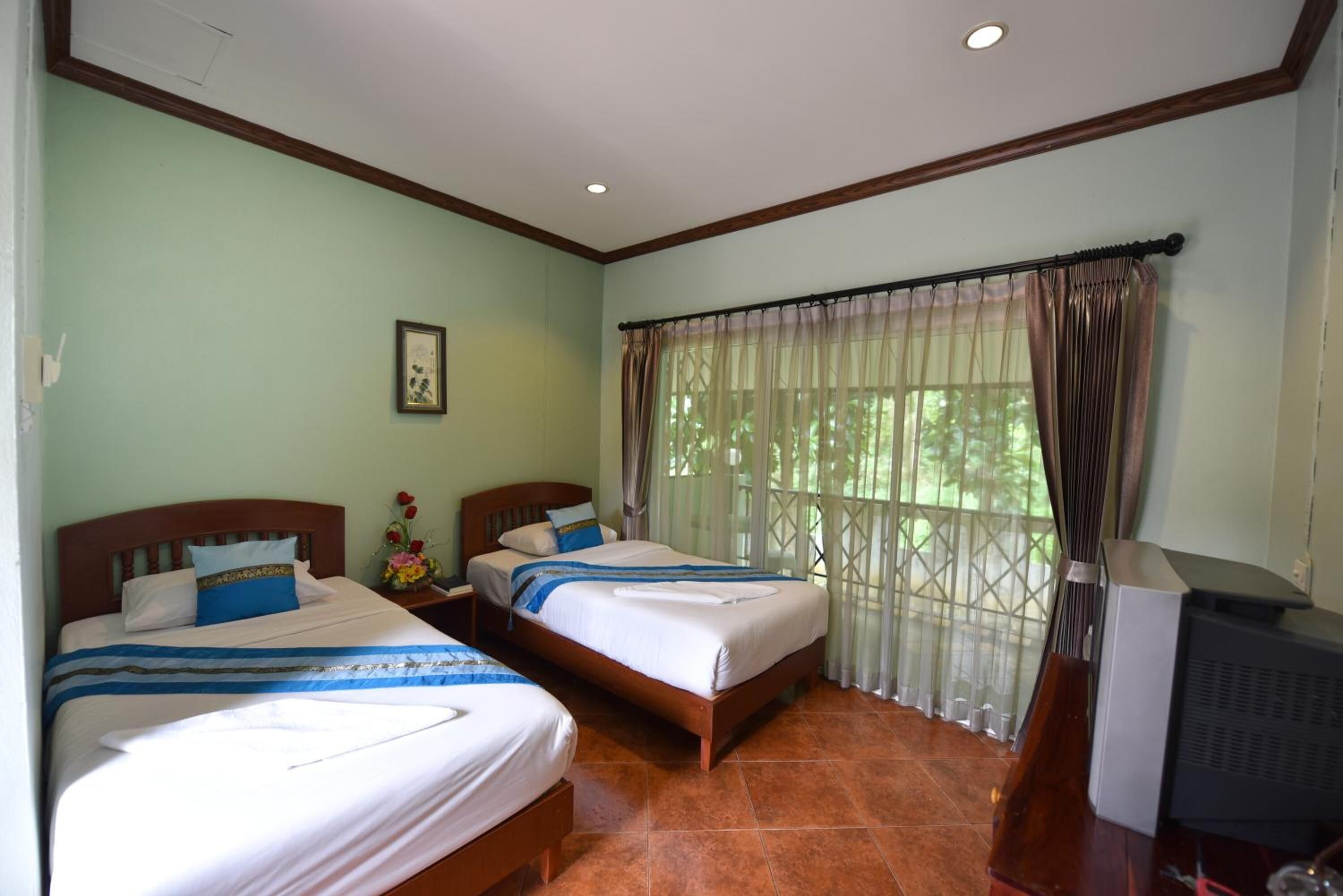 A hotel room with two beds, a TV, and a window with curtains.
