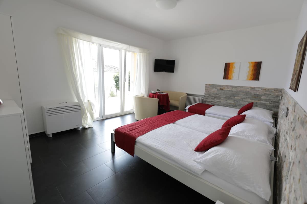 Een hotelkamer met twee bedden, een televisie en een raam met gordijnen.