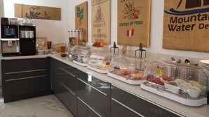 Montaje de bufé con diversos alimentos y una estación de café.