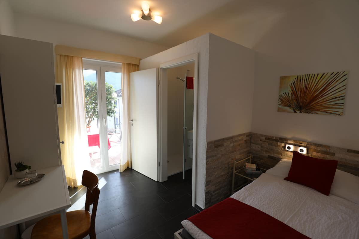 Hotelkamer met een bed, bureau, stoel, douche en uitzicht.