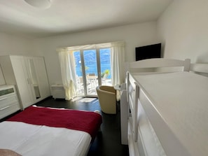 A bedroom with a bed, a chair, a wardrobe, and a television.