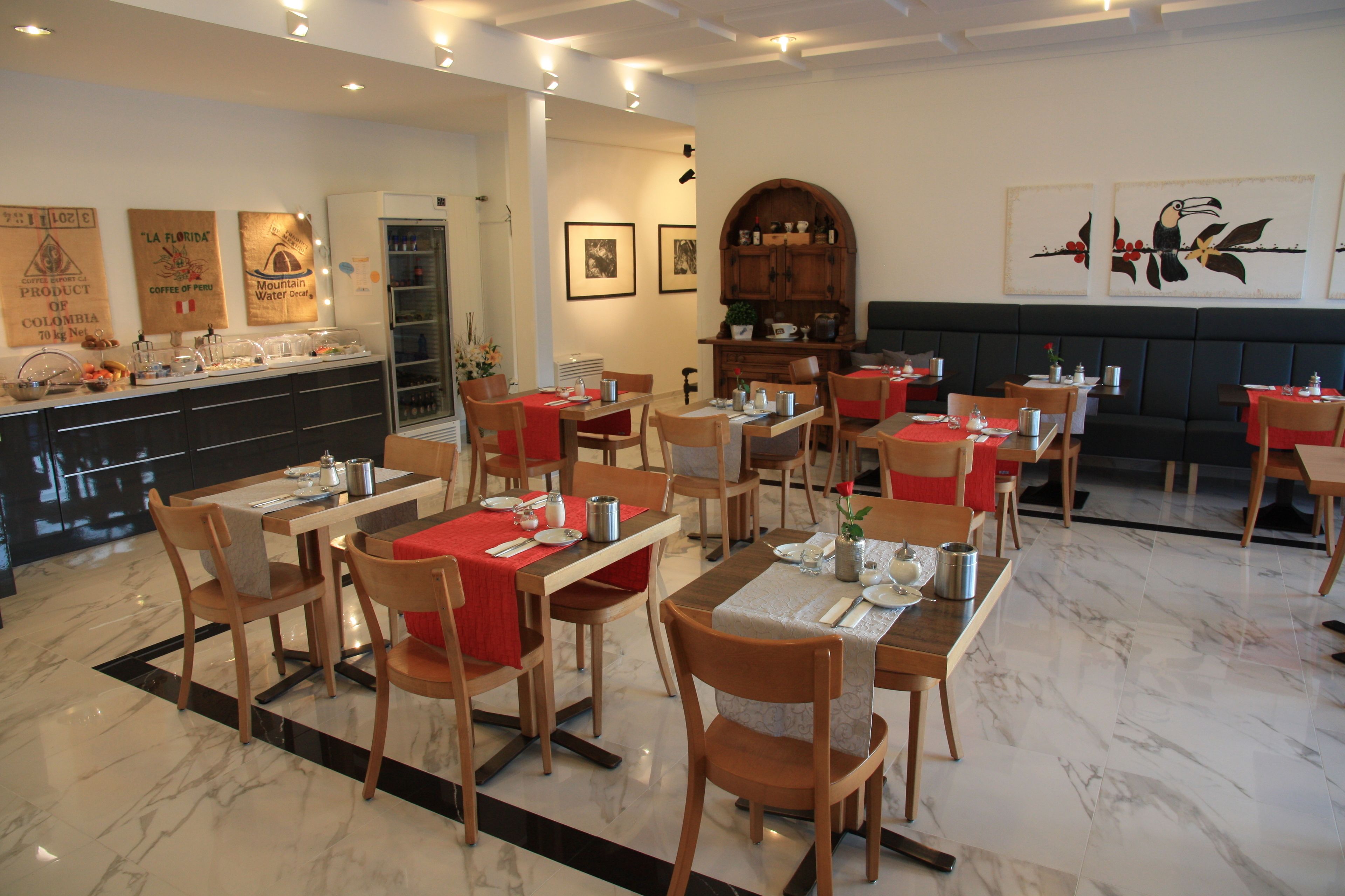 Un restaurante con suelo de mármol, mesas y sillas de madera, y una zona de buffet con diversos alimentos.