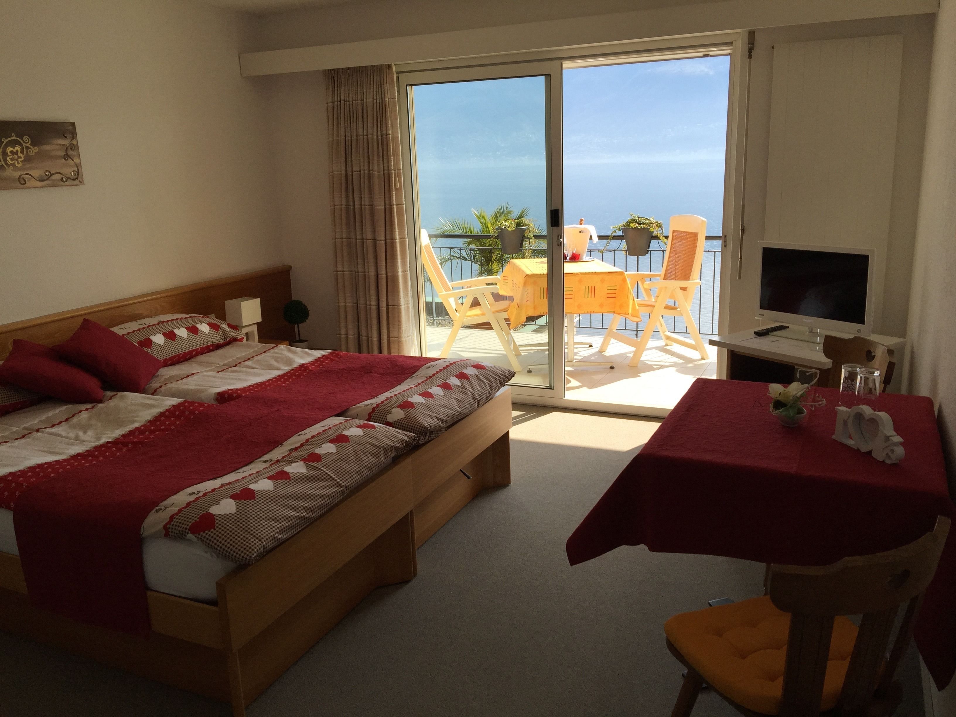 Une chambre d’hôtel avec un lit, un bureau, une chaise et un balcon donnant sur la mer.