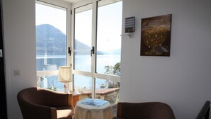 Habitación con vistas a un lago y montañas, con dos sillones, una mesita con lámpara y un cuadro en la pared.