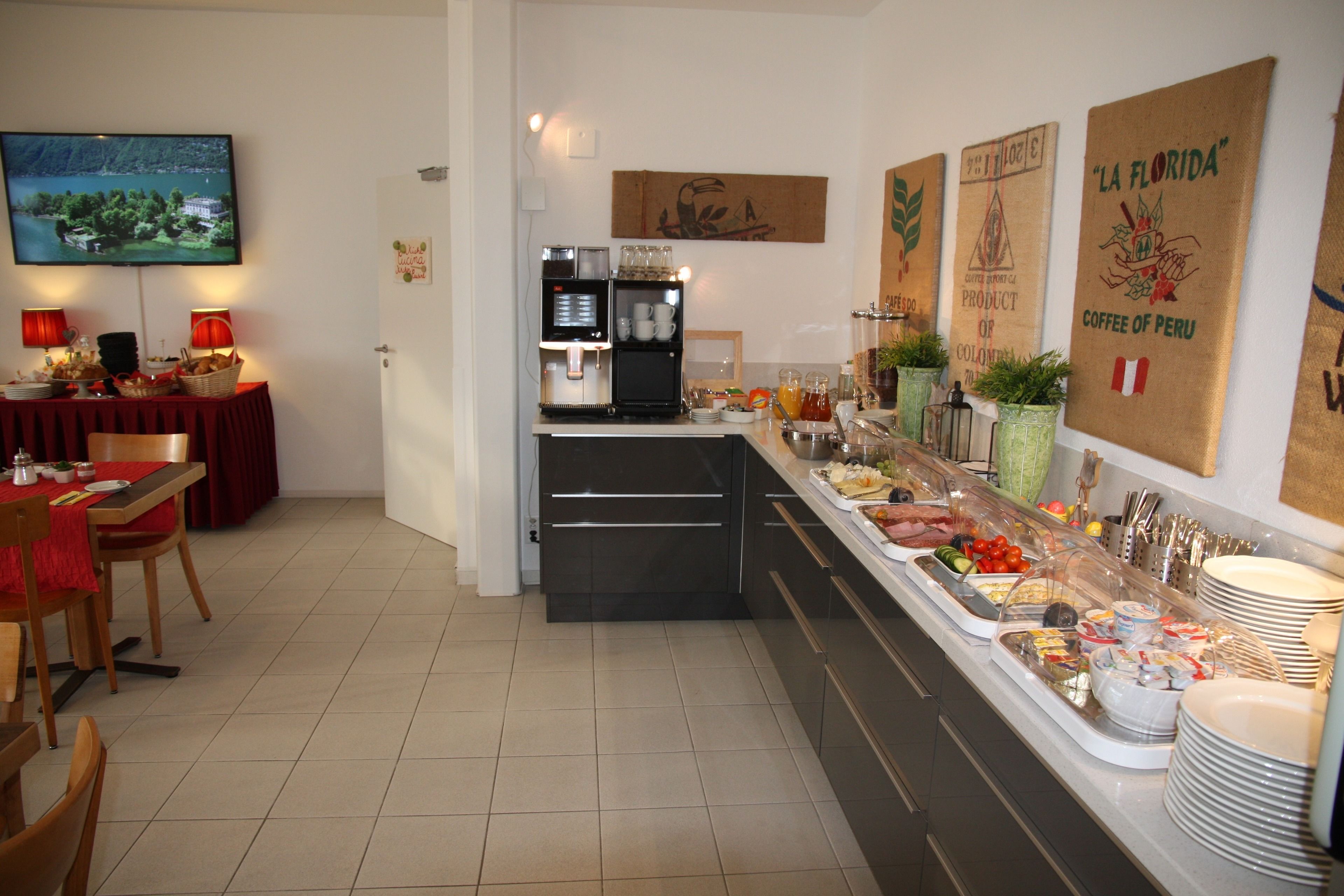 Ein Frühstücksbuffet mit einer Kaffeemaschine, einem Fernseher und verschiedenen Speisen.