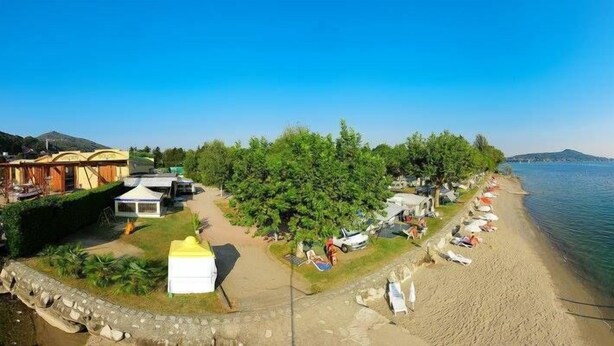 Ein Seeufergrundstück mit Strand, Zelten und einem kleinen Gebäude.