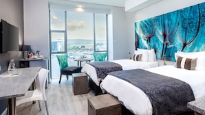 Een hotelkamer met twee bedden, een bureau en een groot raam met uitzicht op de stad.