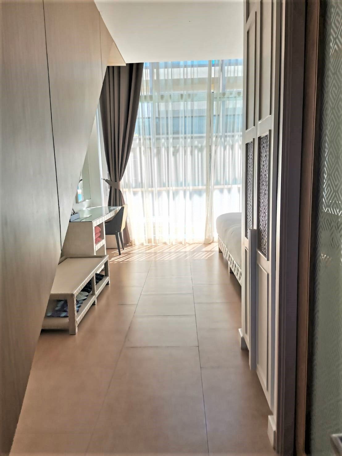 Ein modernes Hotelzimmer mit einem Bett, einem Schreibtisch und einem großen Fenster mit Vorhängen.