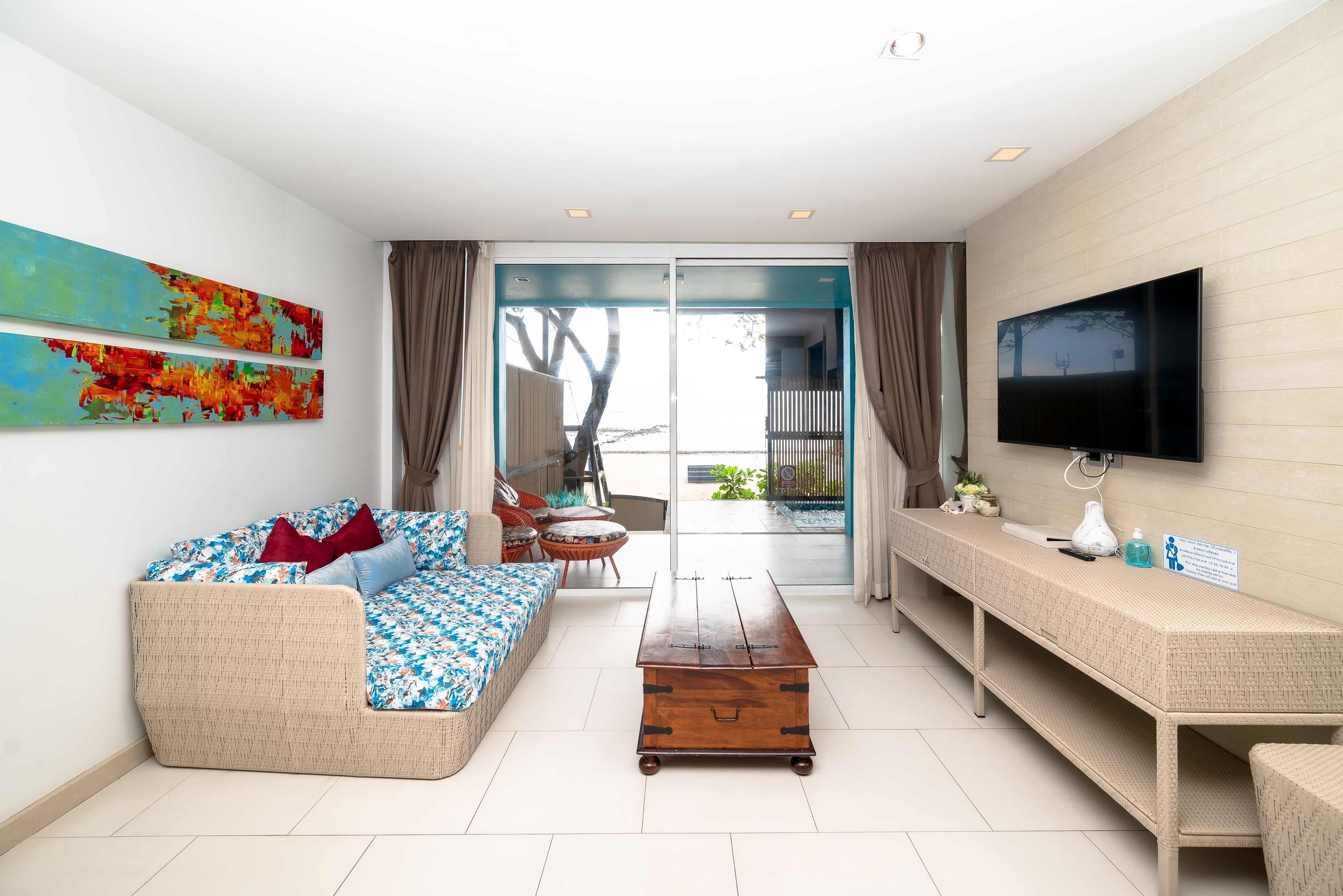 A modern living room with a sofa, coffee table, TV, and artwork on the wall.