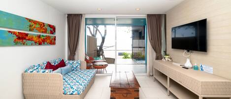A modern living room with a sofa, coffee table, TV, and artwork on the wall.