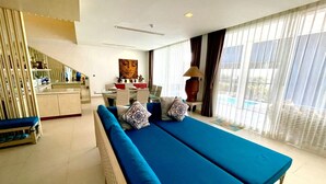 Una habitación de hotel moderna con una cama grande, una zona de comedor y vistas al exterior.