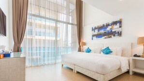 Una habitación de hotel con una cama grande, un escritorio, una silla y una ventana con cortinas.