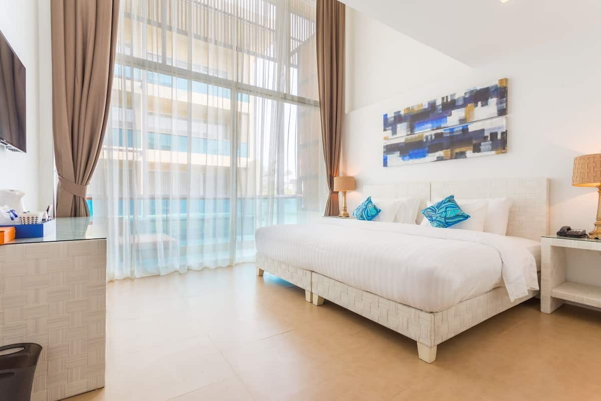 Un cuarto de hotel con una cama grande, un escritorio, una silla, una lámpara y un cuadro en la pared.