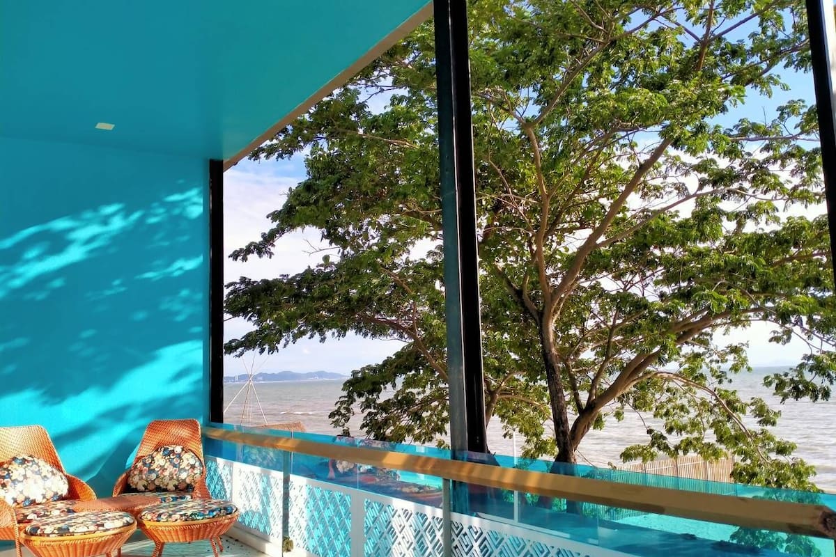 Un balcón con sillones de mimbre y vista al mar.