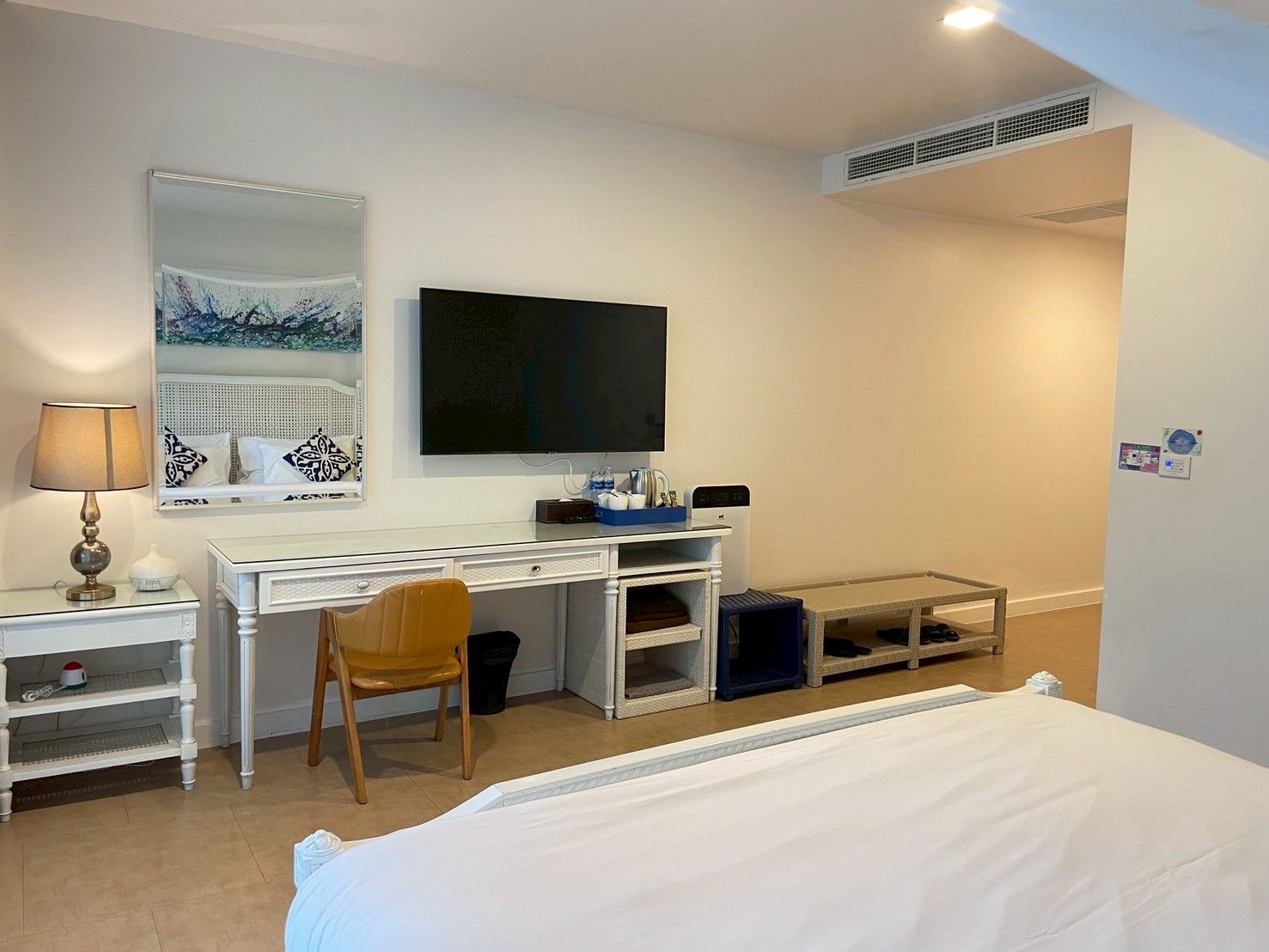 A hotel room with a bed, a desk with a chair, a television, and a mirror.