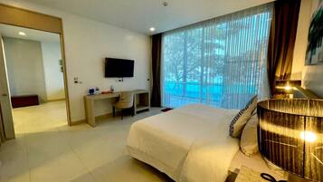 A hotel room with a bed, a desk, a TV, and a large window with curtains.