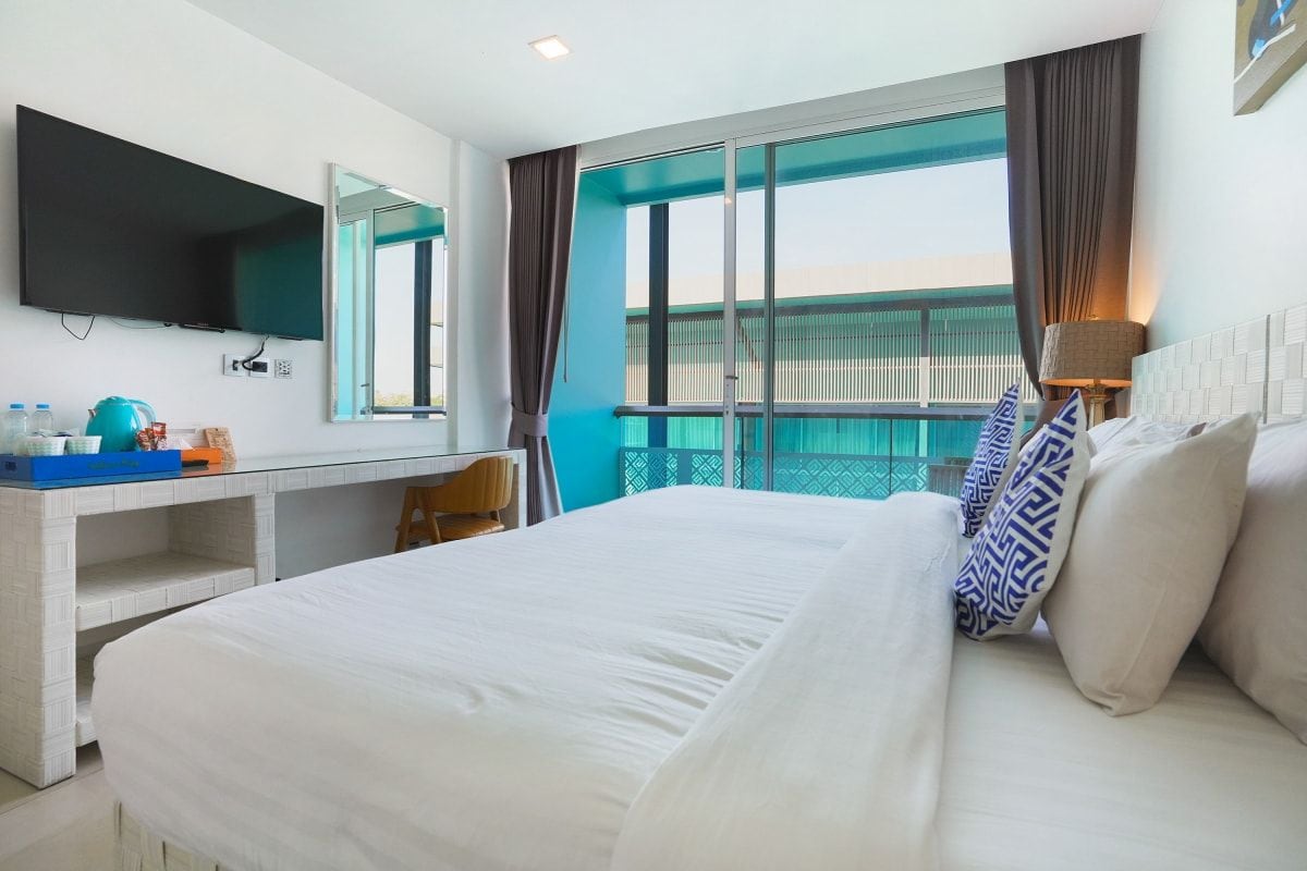 A hotel room with a bed, a desk, a TV, and a window with curtains.