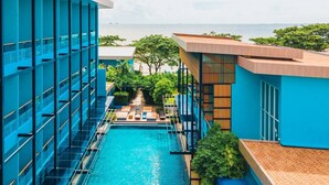 Un hotel moderno con piscina, vistas al mar y un jardín tropical.
