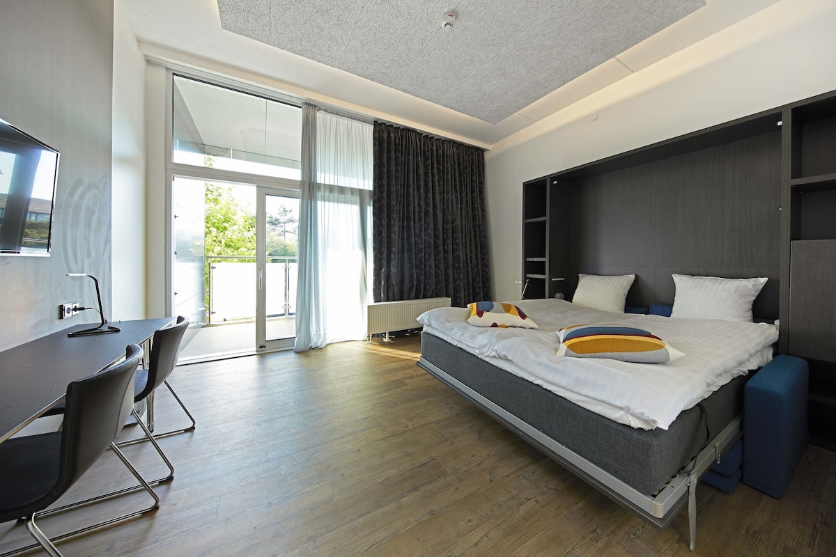 Quarto de hotel moderno com cama, escrivaninha e cadeira.