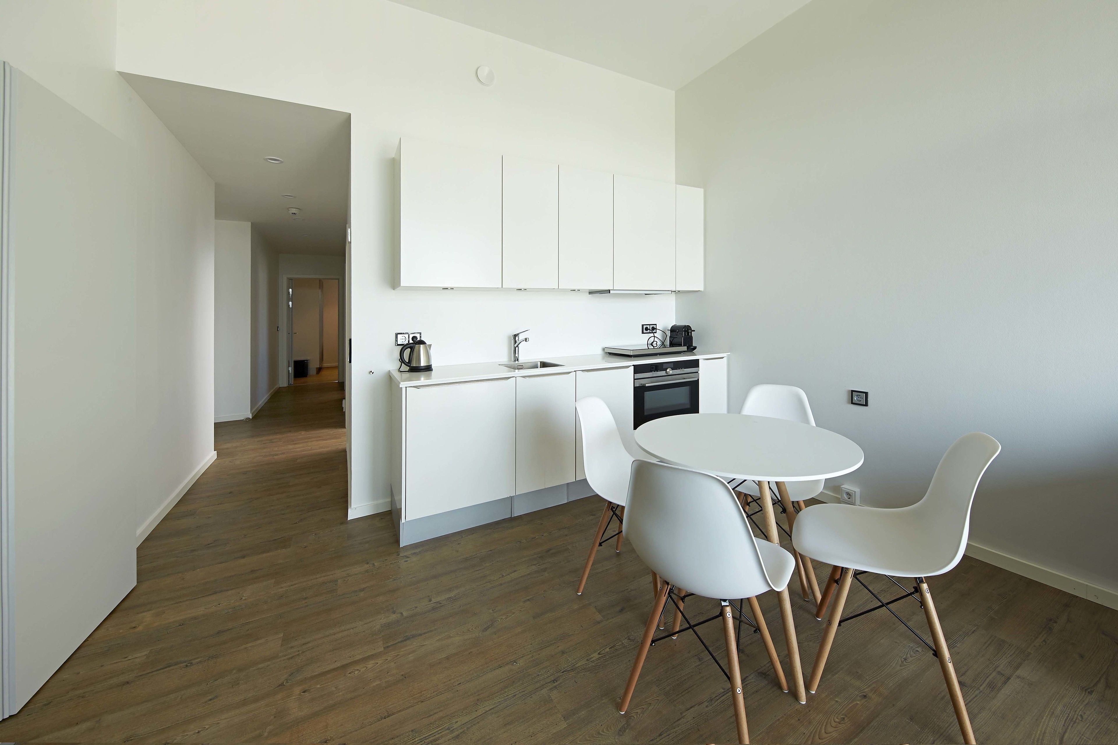 Une cuisine moderne avec des meubles blancs, une table de salle à manger ronde et des chaises blanches.