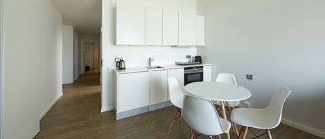 Une cuisine moderne avec des meubles blancs, une table de salle à manger ronde et des chaises blanches.