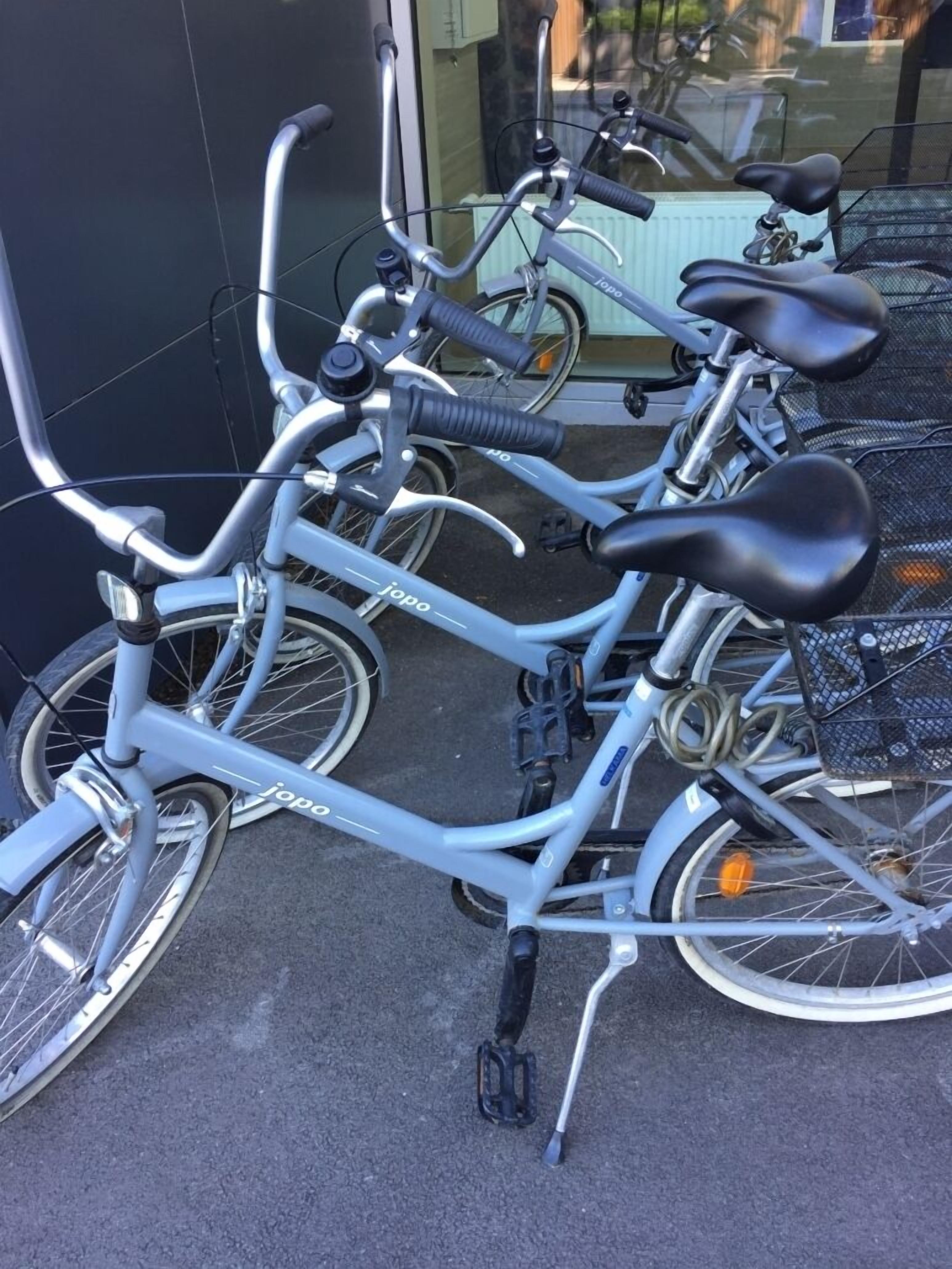 Eine Reihe von Fahrrädern, abgestellt vor einem Gebäude mit Glastür.