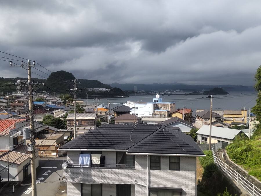 A residential area with houses, a bridge, and a body of water in the distance.