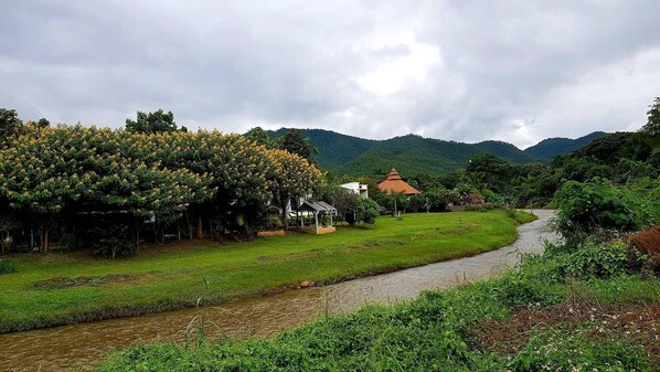 A rural landscape with a river, green fields, and a few houses. - Pai River Villa (Pai)