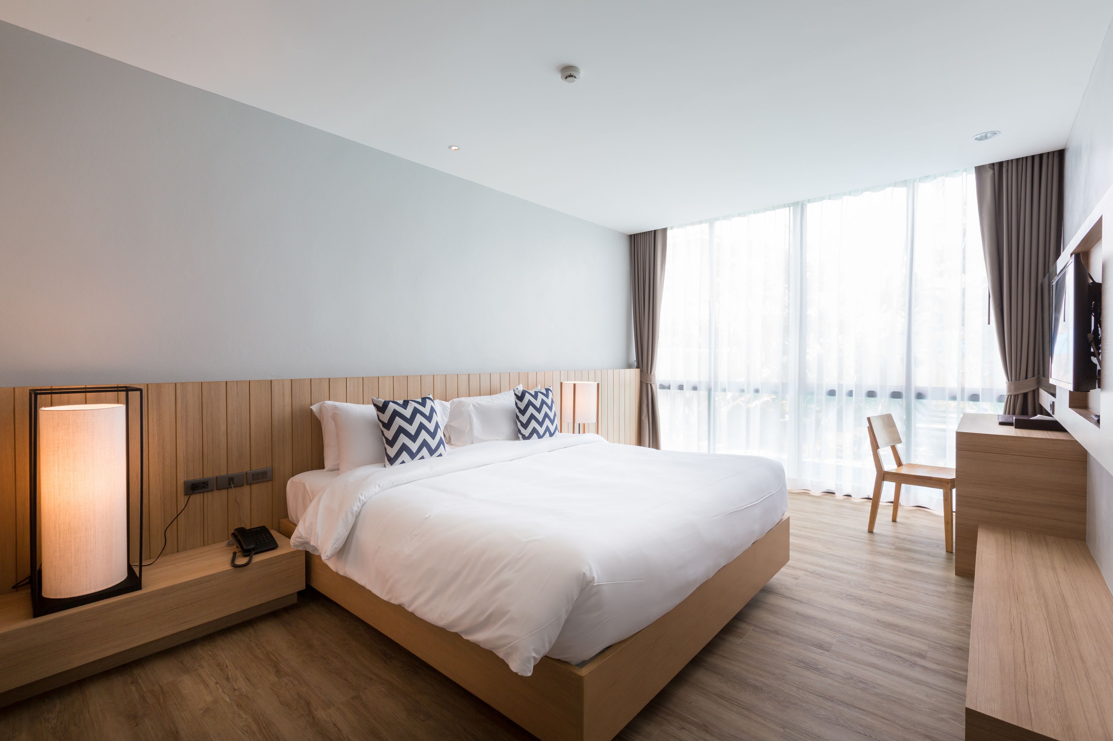 Ein modernes Hotelzimmer mit einem großen Bett, einem Schreibtisch und einem Fernseher.