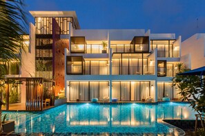 A modern hotel with a swimming pool, multiple balconies, and a well-lit facade. - Asira Boutique HuaHin Hotel (Hua Hin)