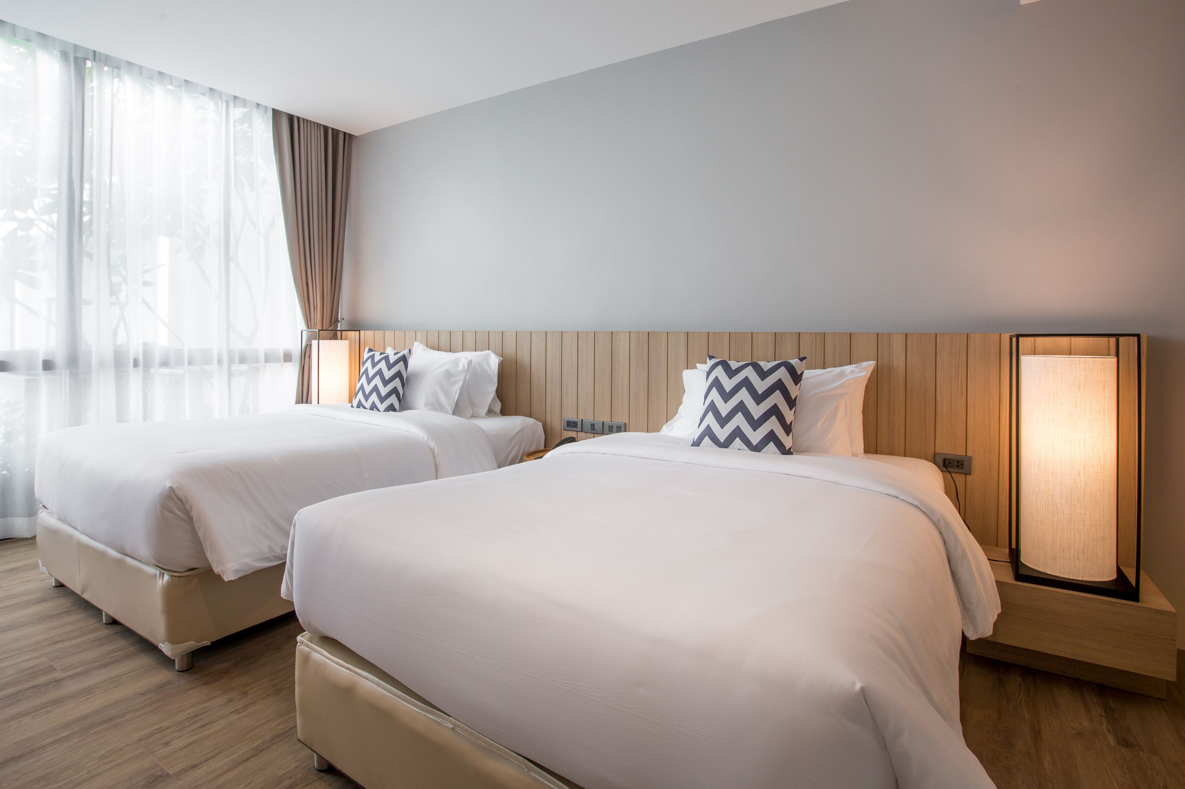 A hotel room with two beds, wooden headboards, and bedside lamps.