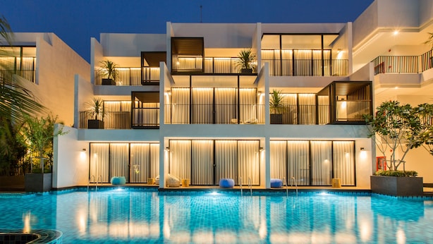 Un hotel moderno de varios pisos con piscina, balcones y plantas de interior.