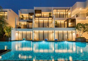 Um hotel moderno de vários andares com piscina, varandas e plantas dentro de casa.