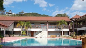A hotel with a swimming pool, a stone staircase, and a red-tiled roof. - Amami Resort Basyayamamura (Amami)