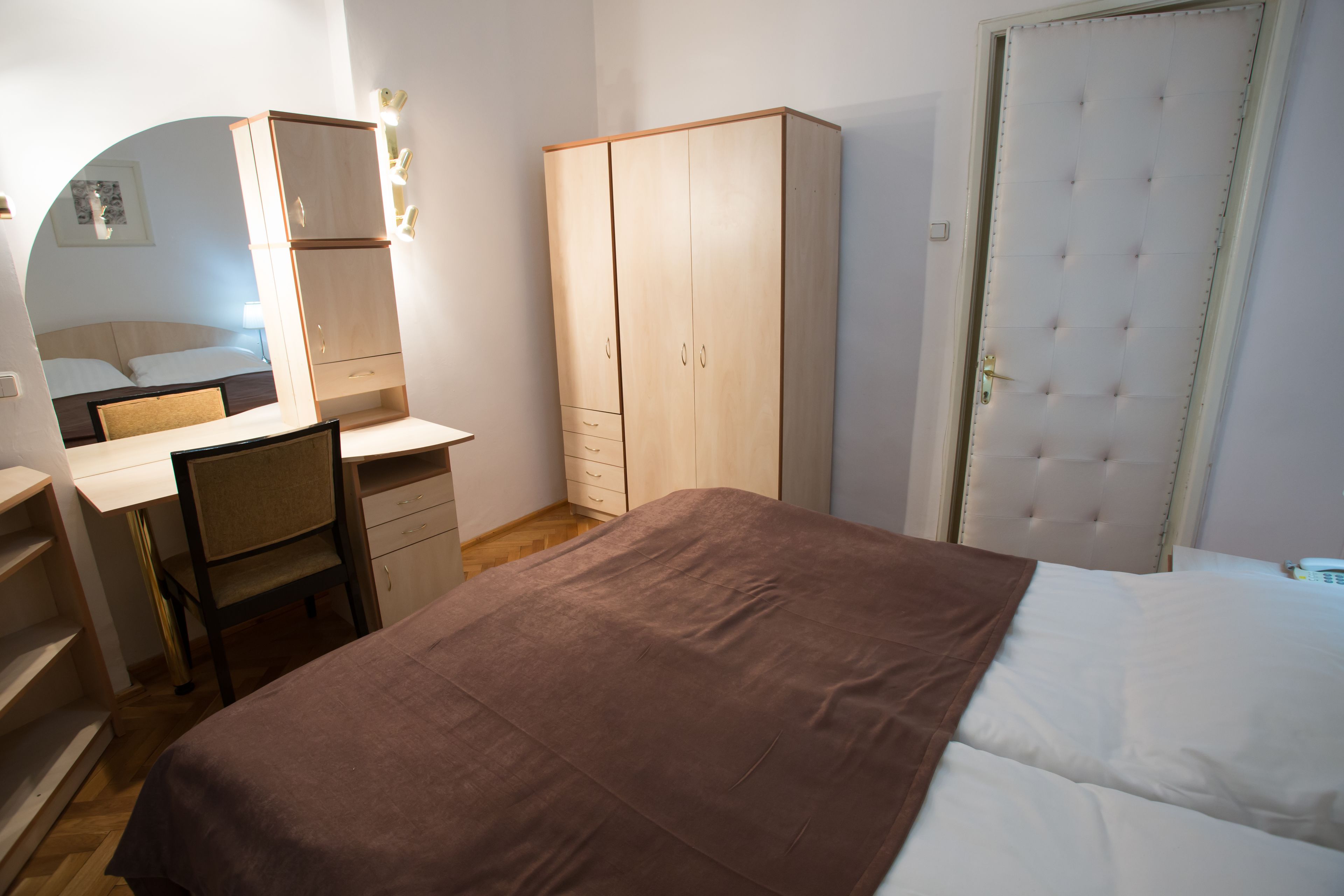 Un dormitorio con cama, escritorio, silla, armario y puerta.