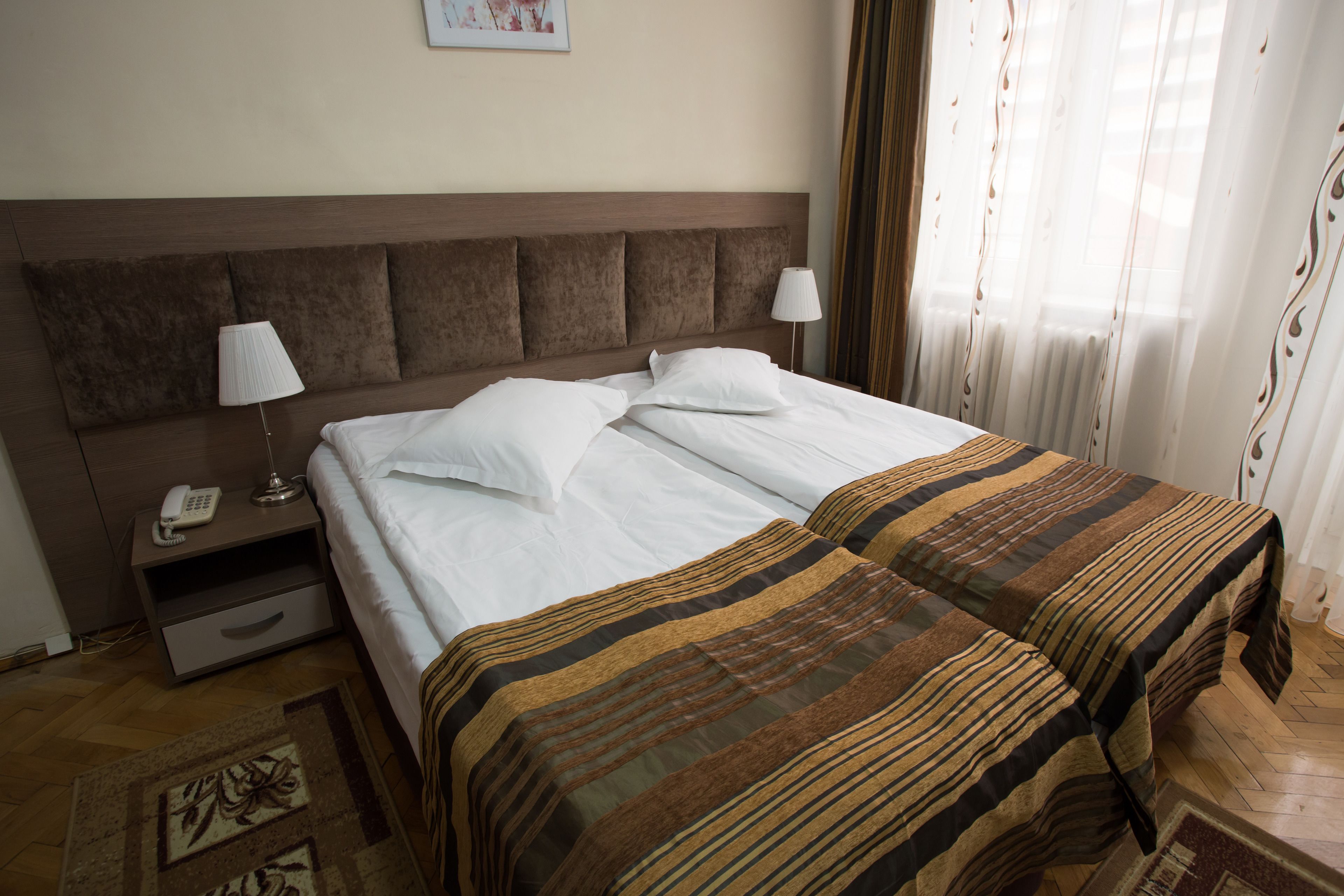 Ein Hotelzimmer mit einem großen Bett, zwei Nachttischen, einer Lampe und einem Telefon.