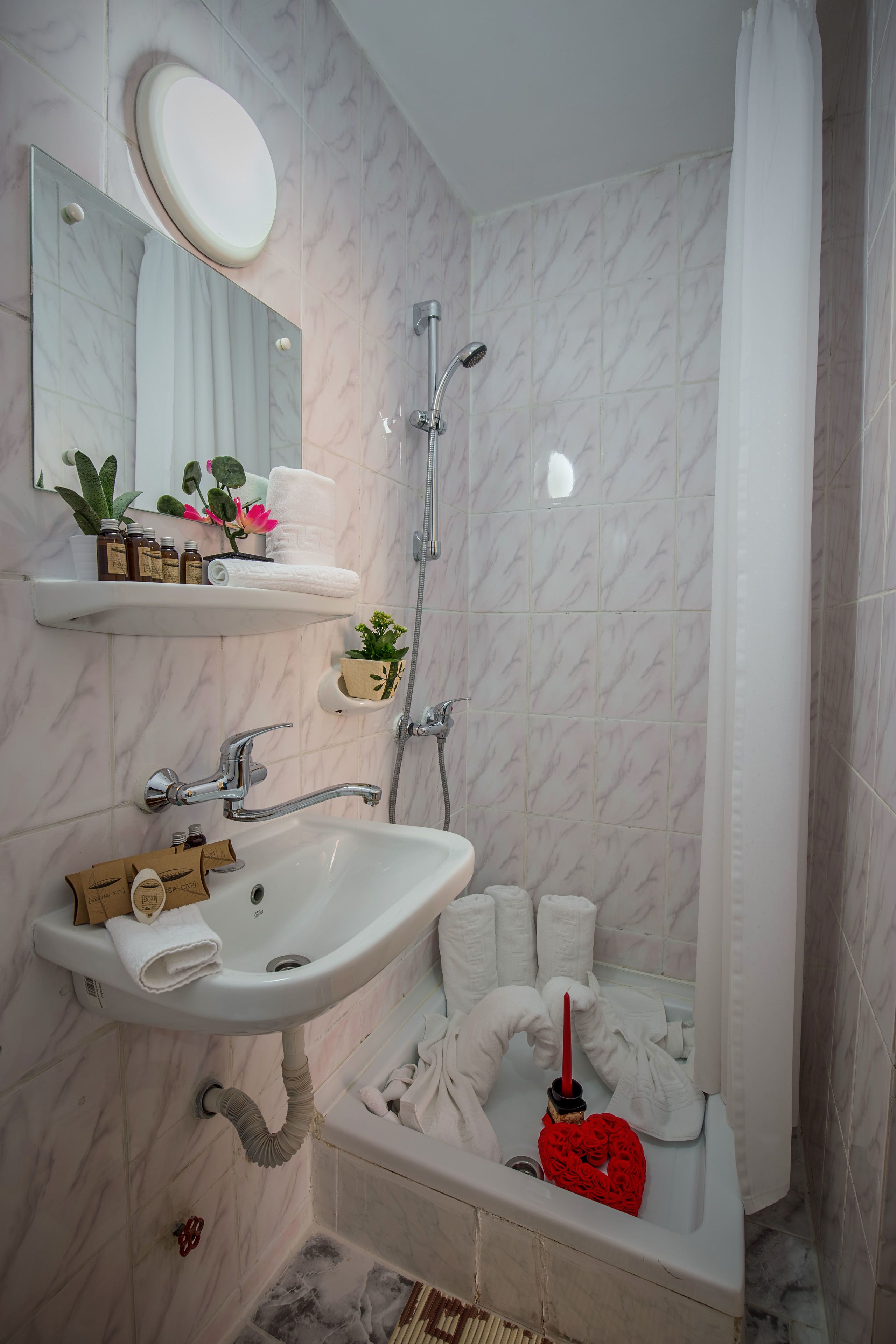 Un baño con lavamanos, espejo, ducha y perchero para toallas.