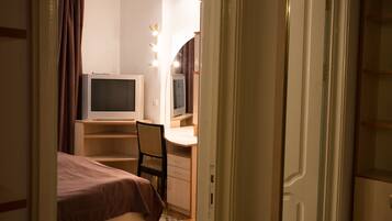 Ein Schlafzimmer mit einem Bett, einem Schreibtisch mit Computer, einem Stuhl und einem beleuchteten Spiegel.