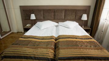 A double bed with a striped bedspread, two bedside lamps, a nightstand with a phone, and a wooden headboard.