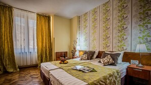 A hotel room with a large bed, a nightstand, a lamp, and a window with curtains. - Hotel Rina Cerbul (Sinaia)